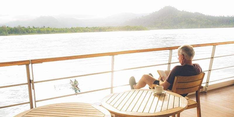 man reading a book on a boat deck